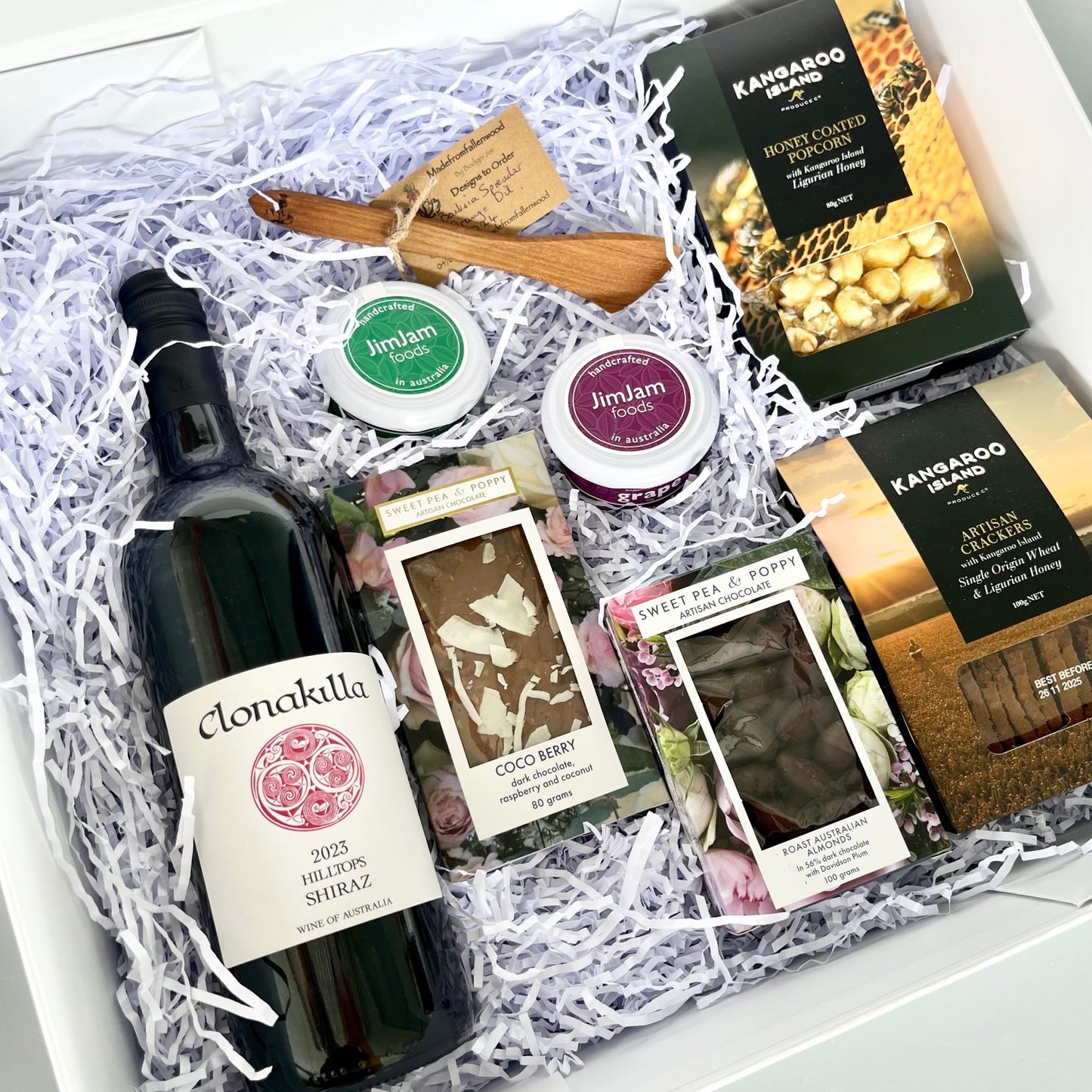 A gift hamper with wine, chocolate, wooden server, gourmet pastes, crackers and popcorn