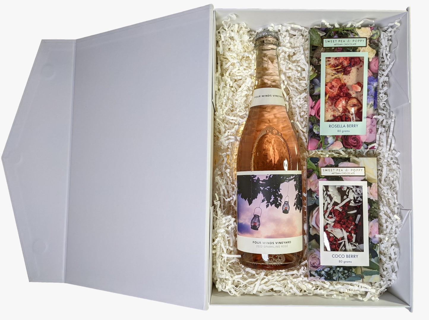 A gift hamper with sparkling rosé wine, a dark chocolate coco berry bar and a white chocolate rosella chocolate bar, presented in a white box with the lid open.