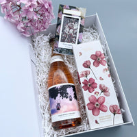 A gift hamper with sparkling wine, chocolate and body cream pamper hamper items