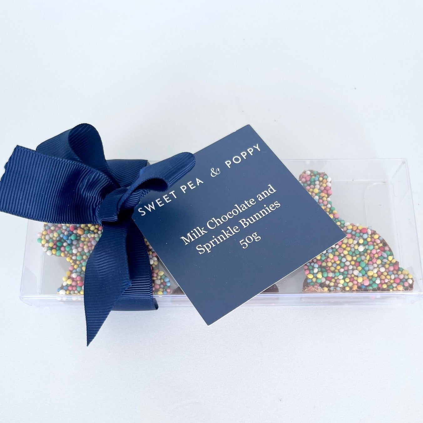 Box of milk chocolate and sprinkle bunnies with a blue ribbon and label on a white background