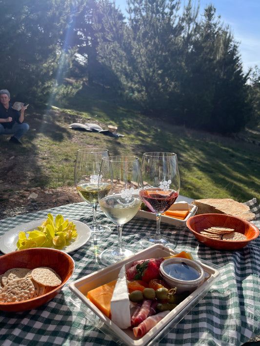 A scenic winery view with a picnic table with wine and cheese platters 