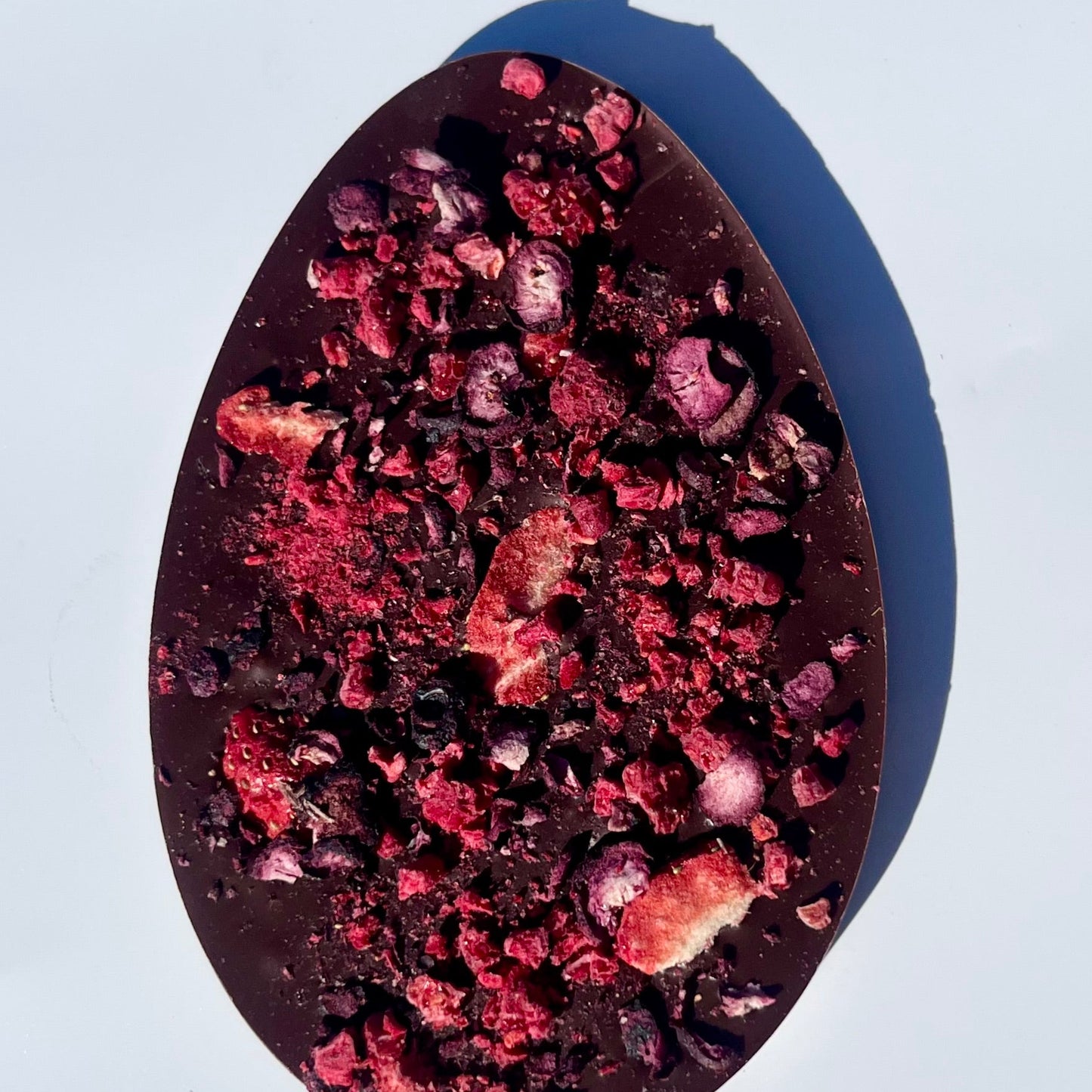 Easter egg shaped dark chocolate bar with berries on a white background