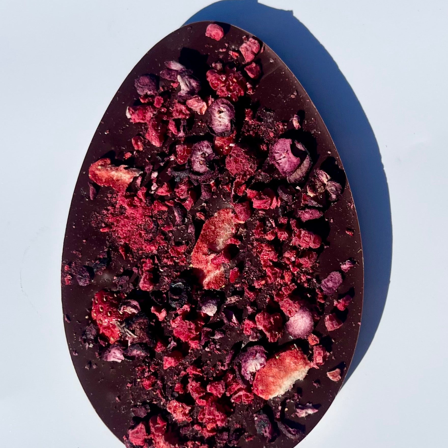Easter egg shaped dark chocolate bar with berries on a white background