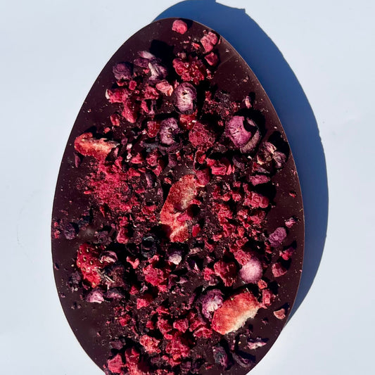 Easter egg shaped dark chocolate bar with berries on a white background