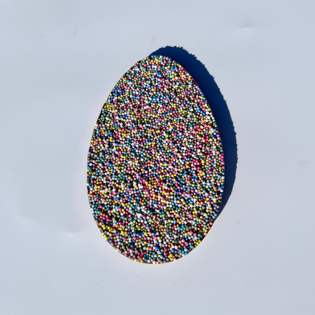 Chocolate Easter egg with multicolored sprinkles on a white background