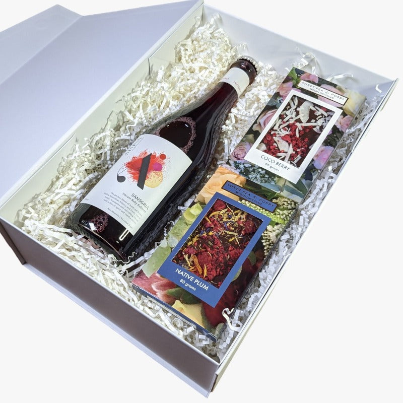 A gift hamper with non-alcoholic wine, a coco berry chocolate bar and a native plum chocolate bar in a white hamper box. 