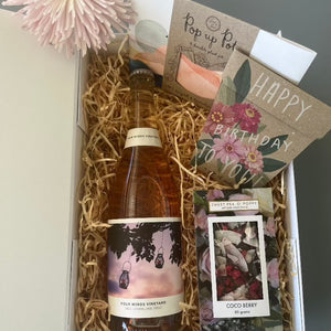 A gift hamper with sparkling wine, a coco berry dark chocolate bar, a seed gift card and a pop up pot gift