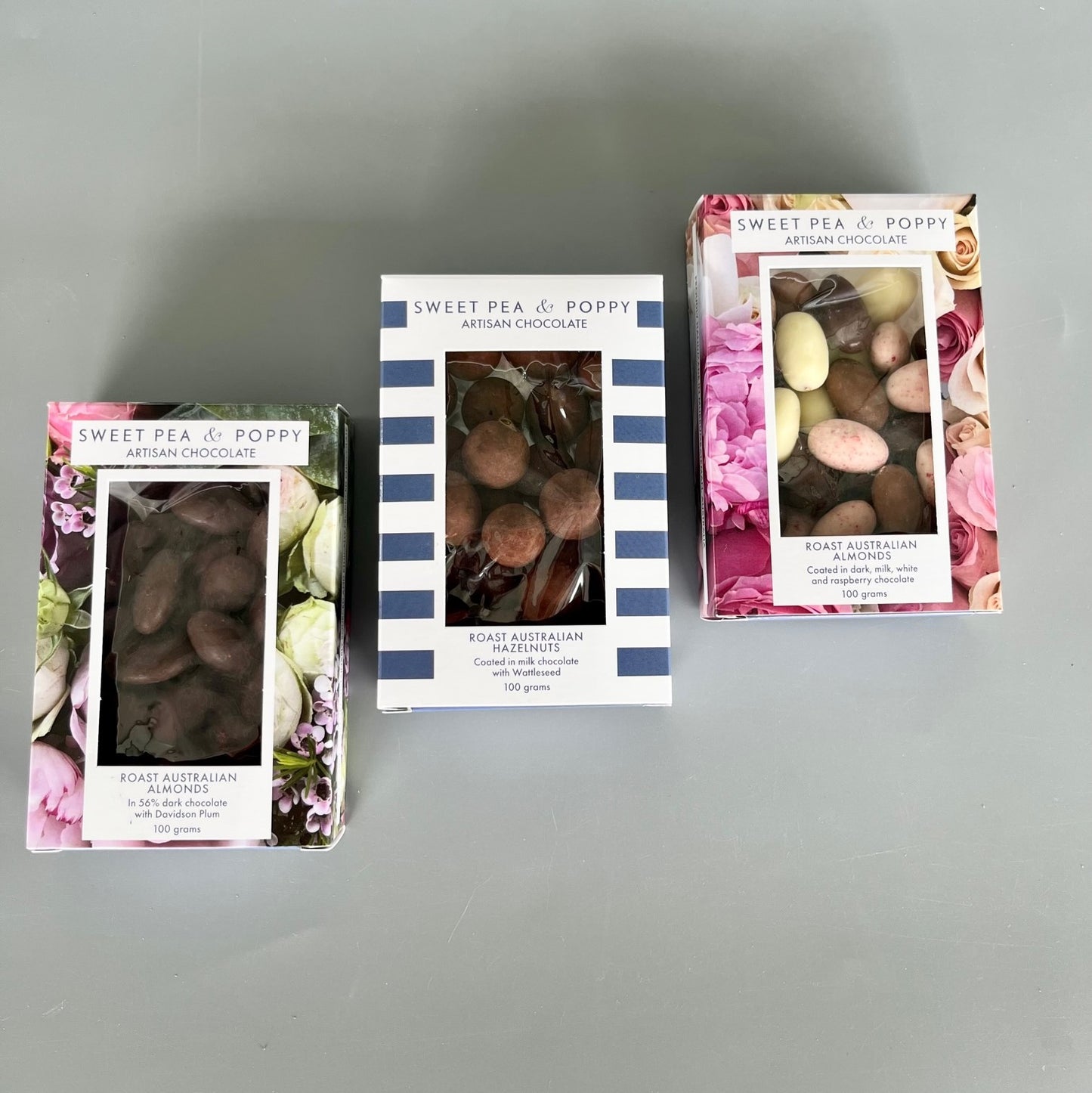 Three boxes of chocolate coated nuts: dark chocolate almonds, milk chocolate Wattleseed hazelnuts, chocolate coated almond medley