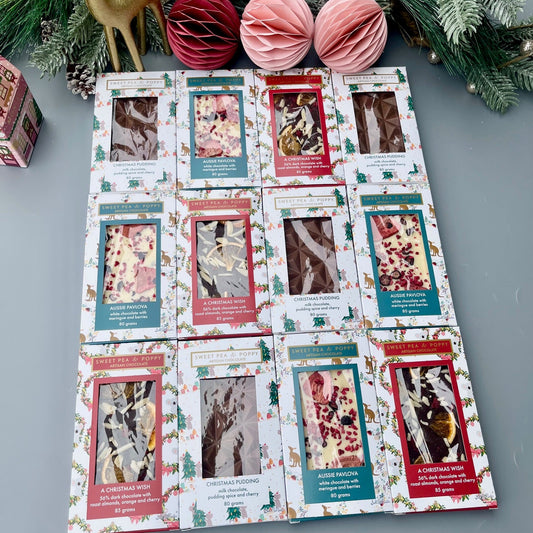Packaged chocolate bars with Christmas images on a gray surface with Christmas decorations.