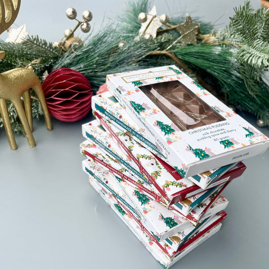 Stack of Christmas-themed chocolate bars with festive decorative elements on a light surface.