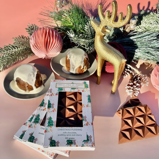 A festive scene with Sweet Pea & Poppy Christmas Pudding artisan chocolate bars and mini Christmas puddings