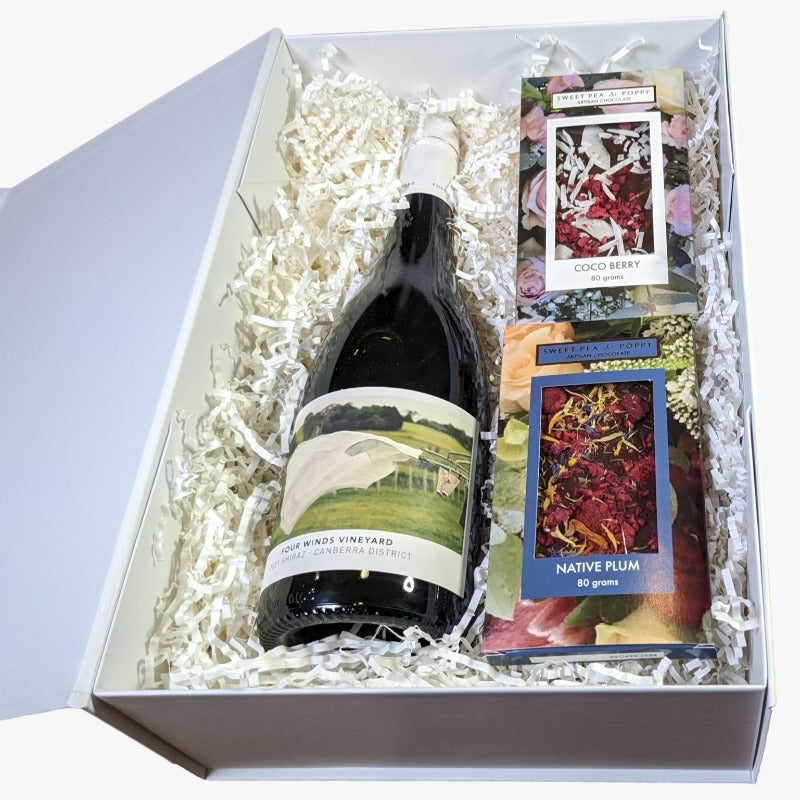 A gift hamper with red wine, a dark chocolate coco berry bar and a dark chocolate native plum chocolate bar, presented in a white box with the lid open. 