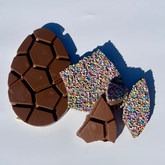Chocolate Easter bars with sprinkles, broken up a white background