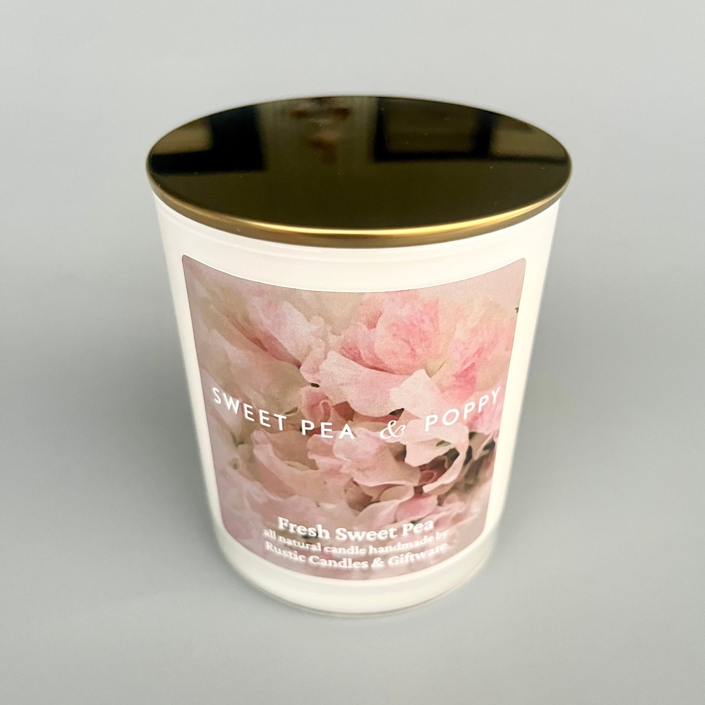Candle with floral design and gold lid on a grey background