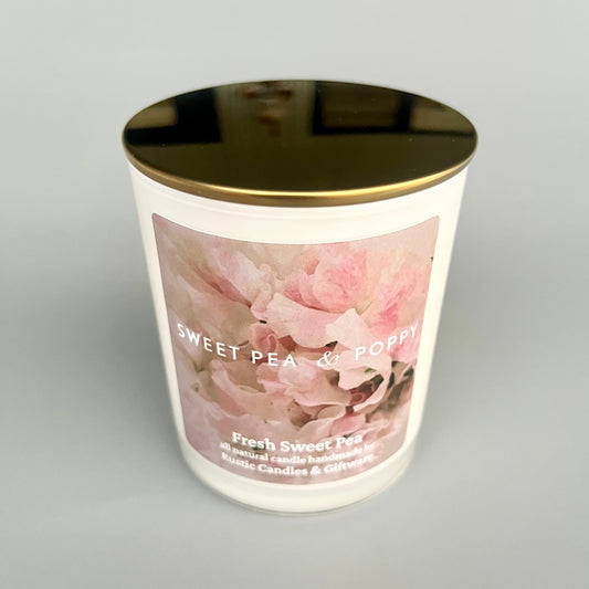 Candle with floral design and gold lid on a grey background
