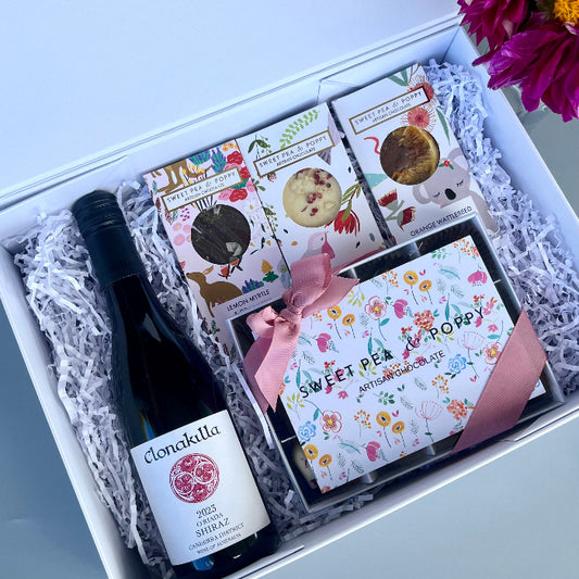 Gift set with a bottle of wine and chocolate boxes in a gift hamper box.