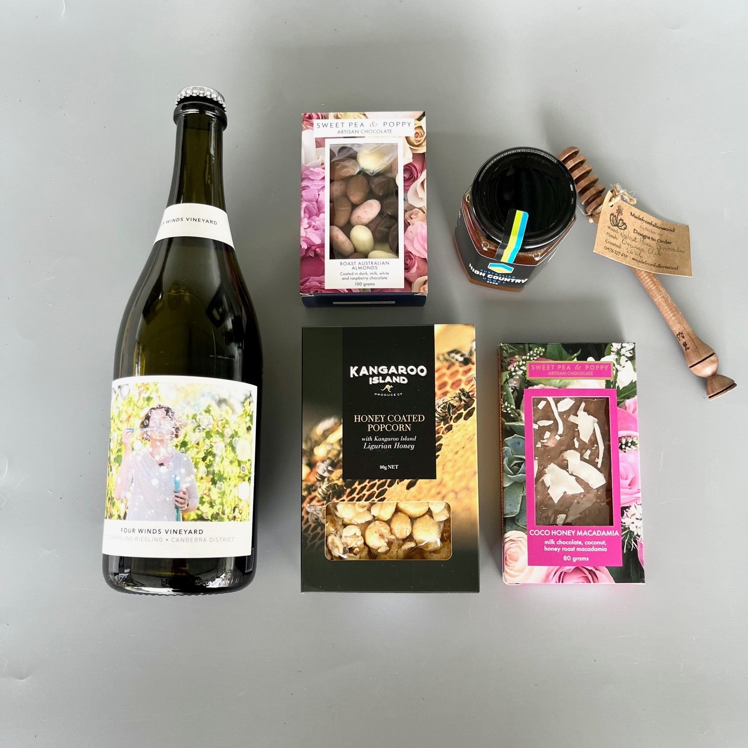 A flatlay selection of wine, chocolate, honey coated popcorn, honey and a honey stirrer