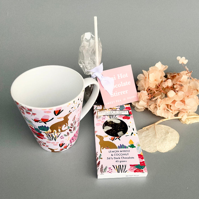 Mug with animal design, chocolate bar packaging, and flowers on a gray background