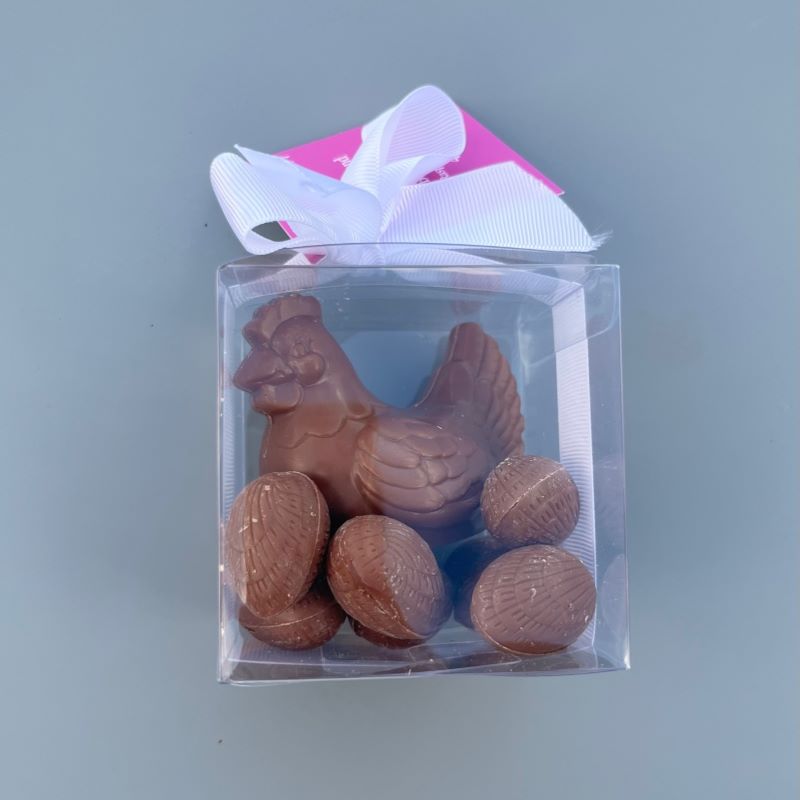 A gift box with a milk chocolate hen sitting on solid milk chocolate Easter eggs