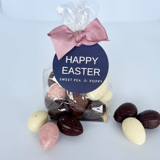Packaged Easter eggs with a pink bow and 'Happy Easter' label on a light grey background