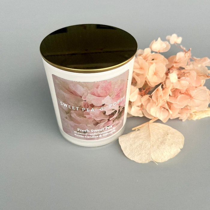 Candle with floral design and gold lid on a grey background