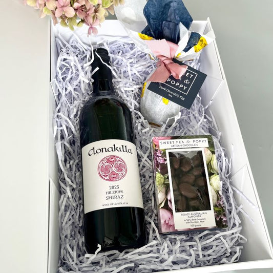 Wine bottle with Clonakilla label in a gift box with flowers and chocolates.