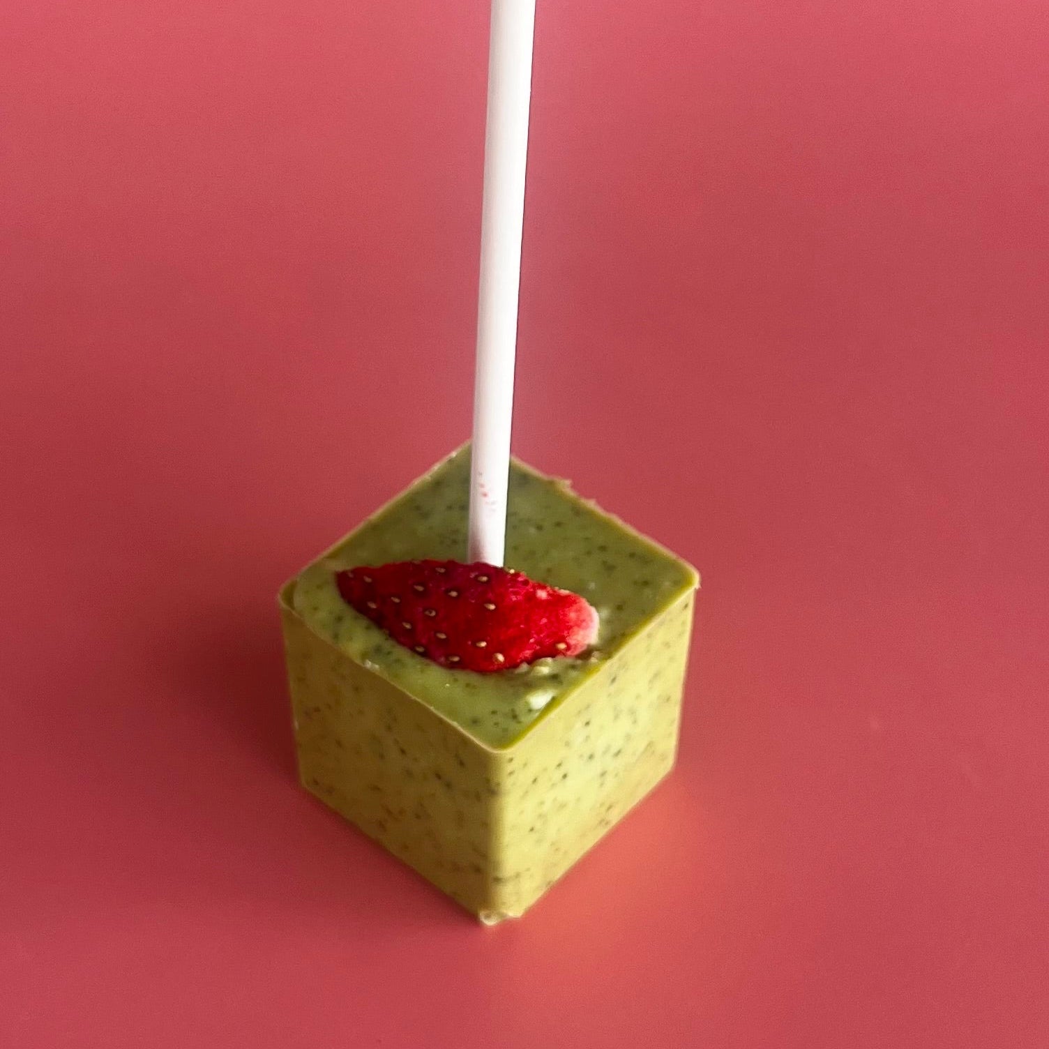 Strawberry Matcha Hot Chocolate Stirrer unpackaged on a pink background 