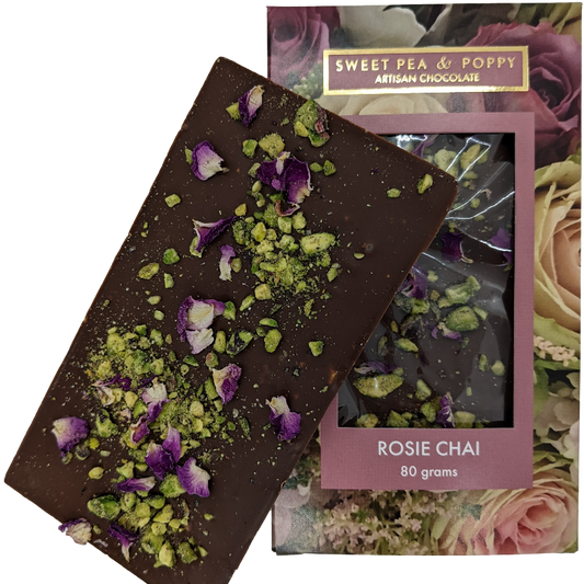 An unpackaged Rosie Chai milk chocolate, chai and pistachio chocolate bar sitting on top of a packaged Sweet Pea & Poppy Rosie Chai chocolate bar