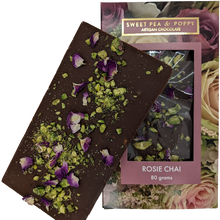 An unpackaged Rosie Chai milk chocolate, chai and pistachio chocolate bar sitting on top of a packaged Sweet Pea & Poppy Rosie Chai chocolate bar