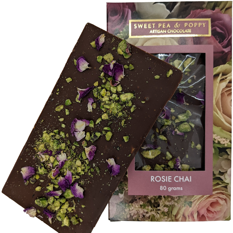 An unpackaged Rosie Chai milk chocolate, chai and pistachio chocolate bar sitting on top of a packaged Sweet Pea & Poppy Rosie Chai chocolate bar