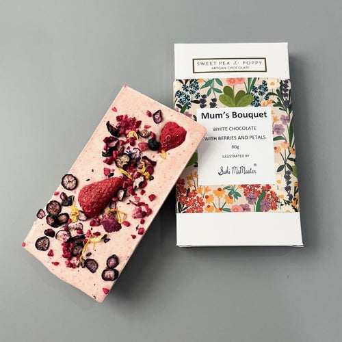 A raspberry white chocolate and berry chocolate bar sitting on top pf a packaged Sweet Pea & Poppy Mum's Bouquet chocolate bar