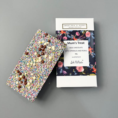 A sprinkle topped milk chocolate bar sitting on top of a packaged Sweet Pea & Poppy Mum's Treat chocolate bar