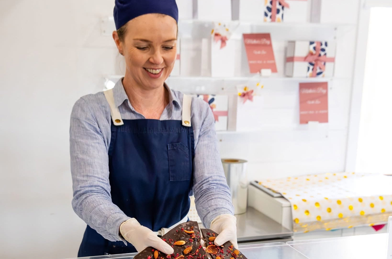 Founder Yasmin Coe holding a slab of handmade chocolate at the Sweet Pea & Poppy chocolate counter