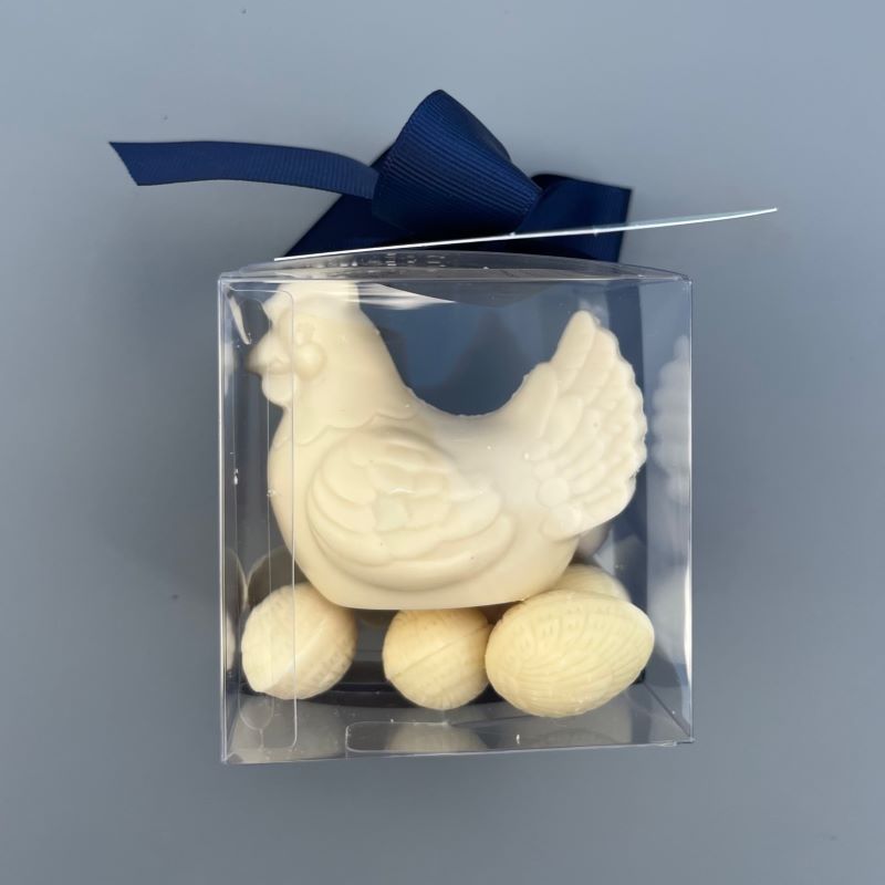 A gift box with a white chocolate hen sitting on solid white chocolate Easter eggs